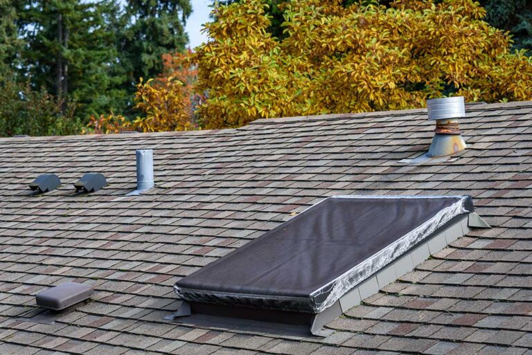 Roofing samples and a rating label on a worktable beside a sunlit residential roof.